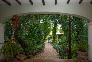 an archway in a garden with trees and plants at Hotel Boutique Casa Quetzal in Valladolid