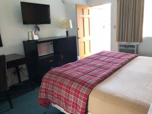 a hotel room with a bed with a red plaid blanket at Desert Lodge in Palm Springs