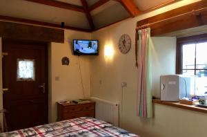 a bedroom with a bed and a tv on the wall at The Stable in Saint Clether