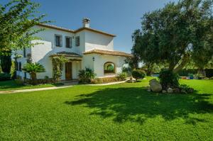 a large white house with a tree in the yard at Villa Miramar, Luxury Villa Rental - Javea in Balcon del Mar
