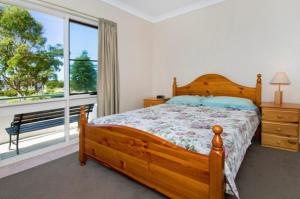 una camera con letto in legno e ampia finestra di Bay Park Gardens 30 1 Warlters Street a Port Macquarie Altre 4 foto