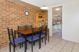 a dining room with a brick wall and a table and chairs at Bay Park Gardens 30 1 Warlters Street in Port Macquarie