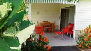 une terrasse couverte d'une maison avec des chaises rouges et une table dans l'établissement Bungalow le manikou, à Le Robert