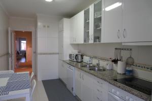uma cozinha com armários brancos, um lavatório e uma mesa em Lenda do Mar em Vila Chã