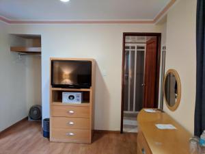 a living room with a tv and a dresser with a tvicterictericter at Hotel del Principado in Mexico City