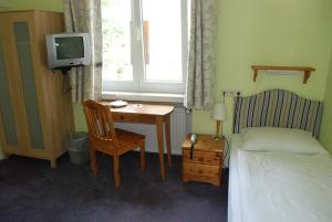 um quarto com uma secretária, uma cama e uma televisão em Finkenhof - Haus Meersmannufer em Hanôver