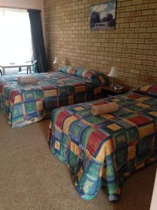a hotel room with two beds and a brick wall at Wudinna Gawler Ranges Motel and Caravan Park in Wudinna