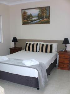 a bedroom with a large bed with two night stands and two lamps at Molika Springs Motel in Moree