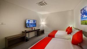 a hotel room with two beds and a flat screen tv at Riccarton Capsule Hotel in Kuala Lumpur