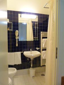 a bathroom with a sink and a toilet and a mirror at Hotel Centrale Byron in Ravenna