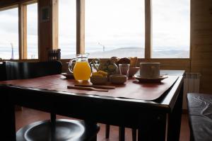 a wooden table with a glass of orange juice on it at Hostería La Soberana in El Calafate