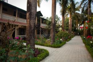 a walkway in front of a resort with palm trees at Sauraha Resort in Sauraha