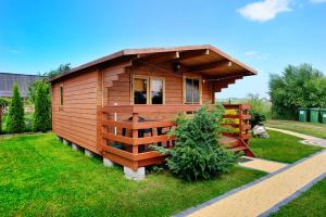 a small wooden cabin in a grassy yard at Domki Rybka in Sarbinowo