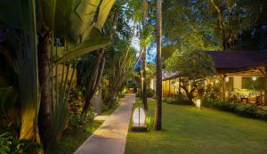 a pathway with palm trees and a bench in a yard at Alaya Dedaun Kuta in Legian