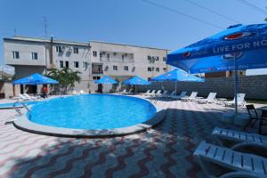 ein großer Pool mit blauen Sonnenschirmen und Stühlen in der Unterkunft White House Hotel in Yerevan