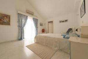 a white bedroom with a bed and a window at Kiriaki House in Paphos City