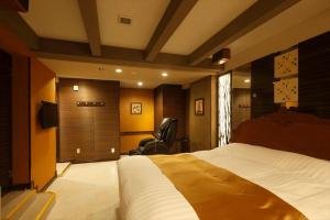 a bedroom with a bed and a chair and clock at Hotel Waltz Chiryu (Adult Only) in Chiryu