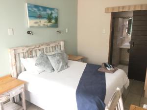 a bedroom with a large white bed and a bathroom at Isle La Breeze Guest House in eMalahleni