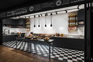 香港Pentahotel Hong Kong, Tuen Mun的厨房里有一个柜台，桌上摆着食物，地板上铺着方格图案