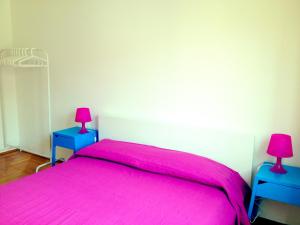 a bedroom with a pink bed and two blue tables at Casa Julia in Cividale del Friuli