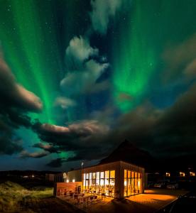 a building under the northern lights in the sky at Arnarstapi Cottages in Stapi