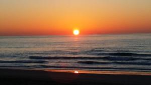 a sunset over the ocean with a beach at Hotel Sant Jordi in Tarragona