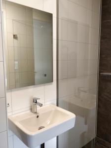 ein weißes Badezimmer mit einem Waschbecken und einem Spiegel in der Unterkunft Antonius Hoeve in Oudenbosch