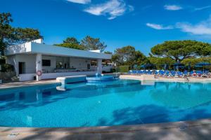 a swimming pool with chairs and a building at BmyGuest - Quinta do Lago Lounge Apartment in Almancil