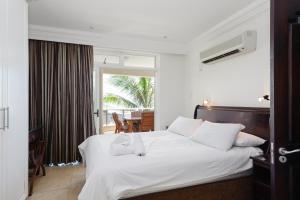 a hotel room with a white bed and a balcony at Ballito Manor Gardens 303 - With Generator in Ballito