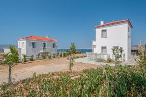 ein weißes Haus und ein Gebäude am Strand in der Unterkunft THOAS Residences in Moúdhros