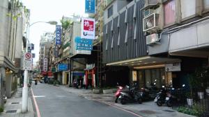 台北的住宿－旅莊商務飯店，一条城市街道上停有摩托车