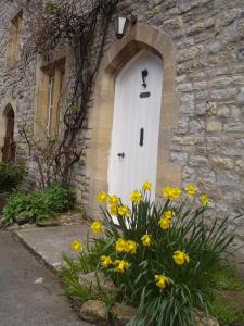 a white door on a stone building with yellow flowers at Mill Lodge in Wells