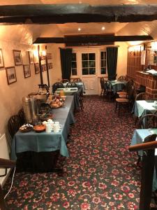 uma sala de jantar com mesas com comida em The Black Bull Inn em Fyfield
