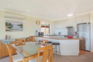 a kitchen with a table and chairs and a refrigerator at Beach Breakers Apartment Stunning Views in Kianga