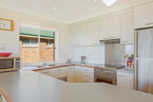 a kitchen with white cabinets and stainless steel appliances at Beach Breakers Apartment Stunning Views in Kianga