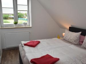 グロース・シュヴァンセにあるCozy Holiday Home in Gross Schwansee with Saunaのベッドルーム1室(白いベッド1台、赤いタオル付)