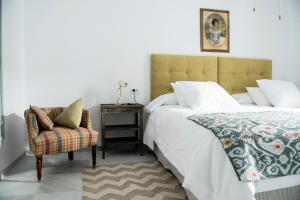 a bedroom with a bed and a chair at Palacio Mármoles in Seville