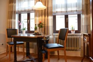 una sala da pranzo con tavolo, sedie e finestre di Reisekultouren Apartments Detmold a Detmold