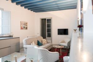 a living room with white walls and a blue ceiling at Palacio Mármoles in Seville +32 photos