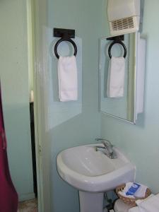 ein Badezimmer mit einem Waschbecken, einem Spiegel und Handtüchern in der Unterkunft American Inn Motel in Many
