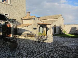 a building with a stone courtyard with benches in front of it at Il Fortilizio in Pietrelcina