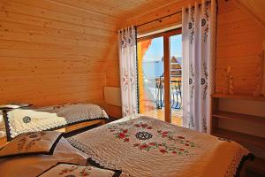 two beds in a room with a window at Osada domków Baca in Poronin