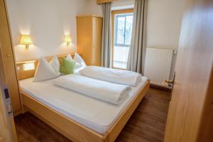 - une chambre avec un lit doté de draps blancs et une fenêtre dans l'établissement Mountain Living Apartments, à St. Valentin auf der Haide