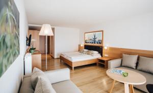 a living room with a couch and a bed at Hotel SeeRose in Bodensdorf