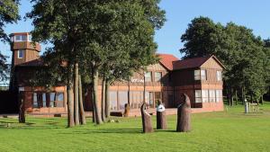 a large building with trees in front of it at Viešbutis Ventainė in Ventė