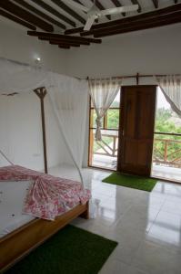a bedroom with a bed with a canopy and green rugs at Shamba Lodge in Nungwi