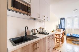 a kitchen with white cabinets and a black sink at Premium Key-Apartaments Śródmieście in Warsaw