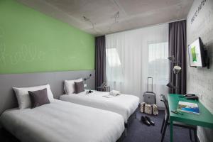 a hotel room with two beds and a green wall at ibis Styles Budapest Airport in Vecsés +88 photos