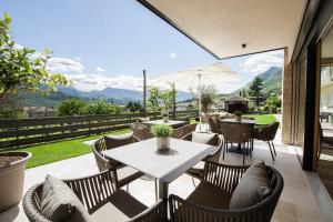 a patio with tables and chairs and a view of the mountains at Haus Gregori in Caldaro