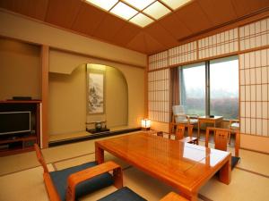a living room with a wooden table and a television at Izumigo Kiyosato Kogen Hotel in Hokuto +10 photos
